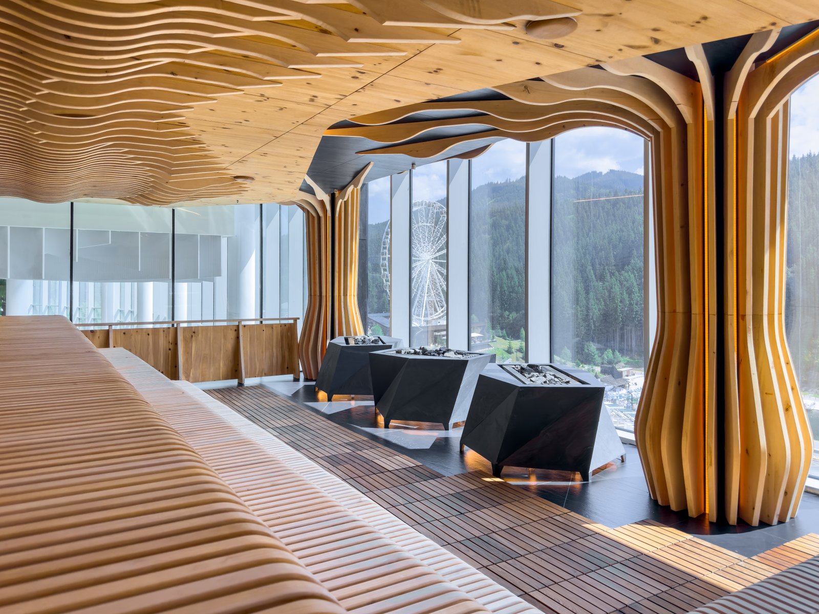 Modern sauna interior featuring wavy wooden panels and large panoramic windows overlooking the forested mountains. A stylish fusion of architecture and nature.